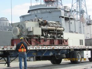 custom metal fabricated ship engine on truck trailer with ship in background