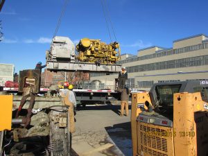 custom metal fabricated machine engine being hoisted by workers