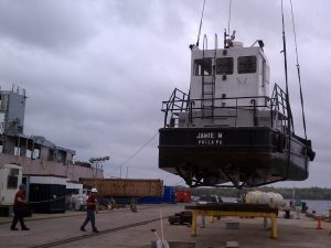 ship being raised onto dry dock platform by crane on overcast day