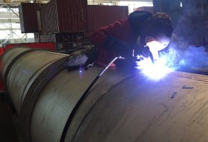 Worker welding custom metal ship component