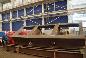 custom metal fabricated component for ship building being raised on by a crane